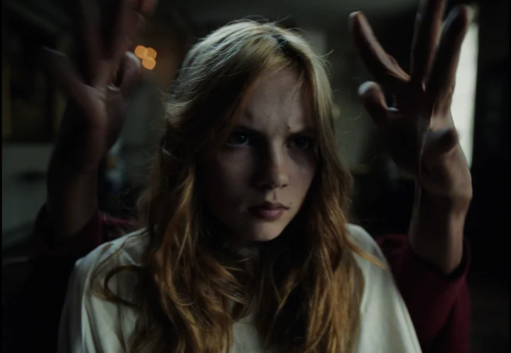 A young woman surrounded by outstretched hands in Vibrations